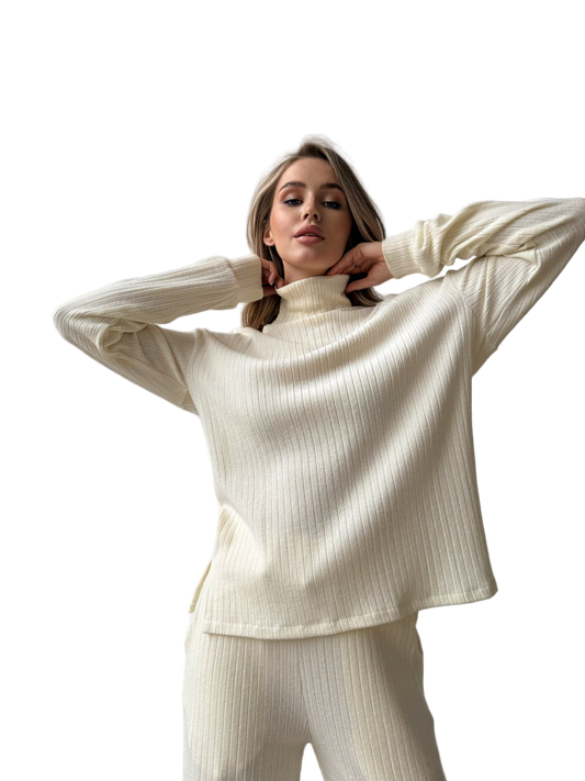 Woman wearing a cream ribbed sweater and pants on a white background