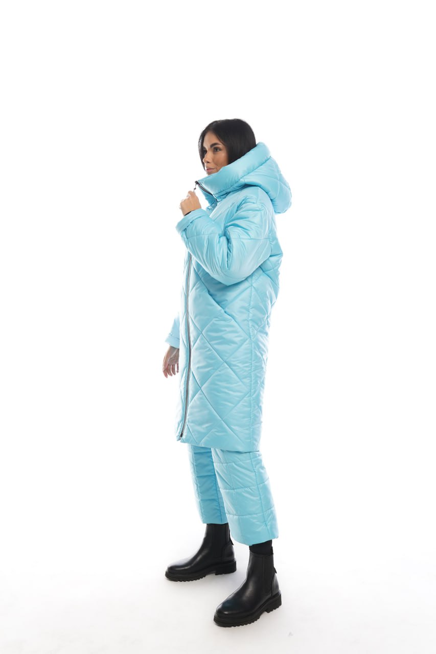 Person wearing a light blue quilted jacket and pants on a white background