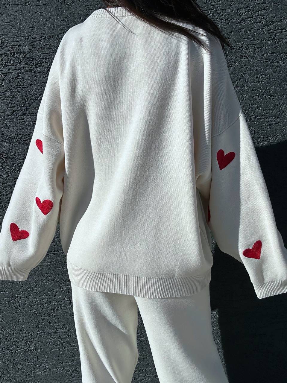 White sweater with red heart patterns on a dark background
