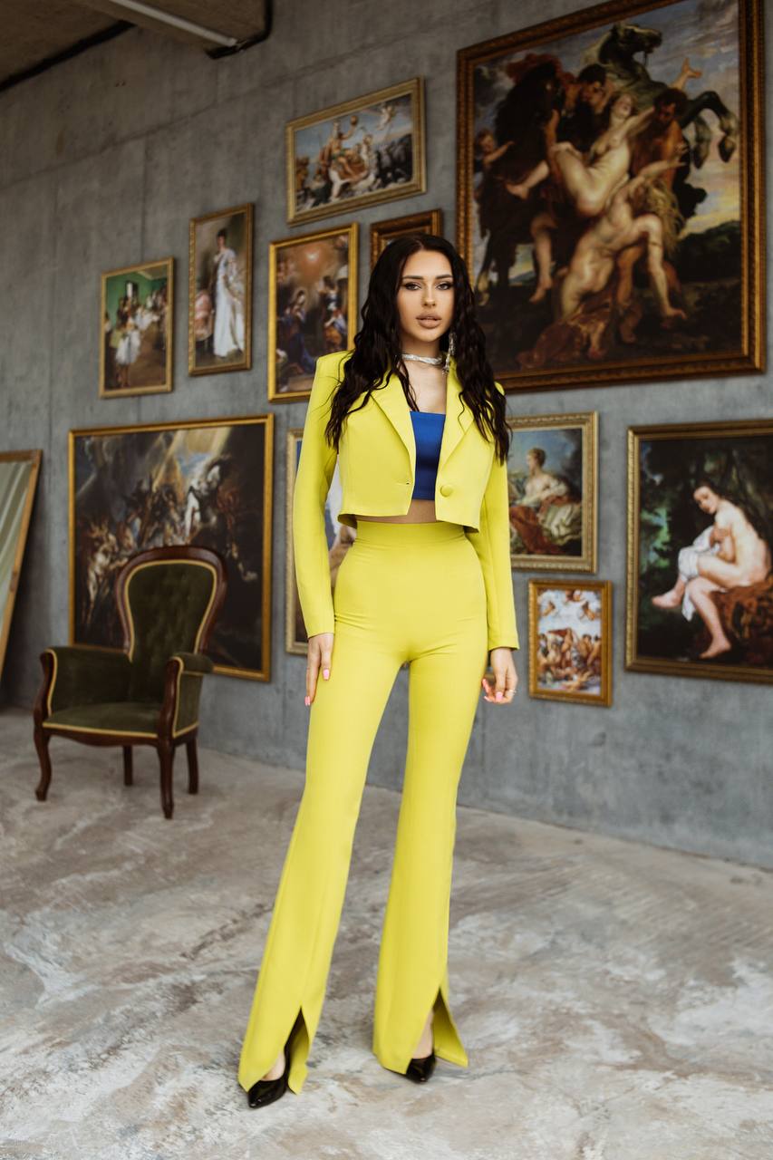 Woman in a yellow outfit standing in an art gallery with classical paintings on the wall.