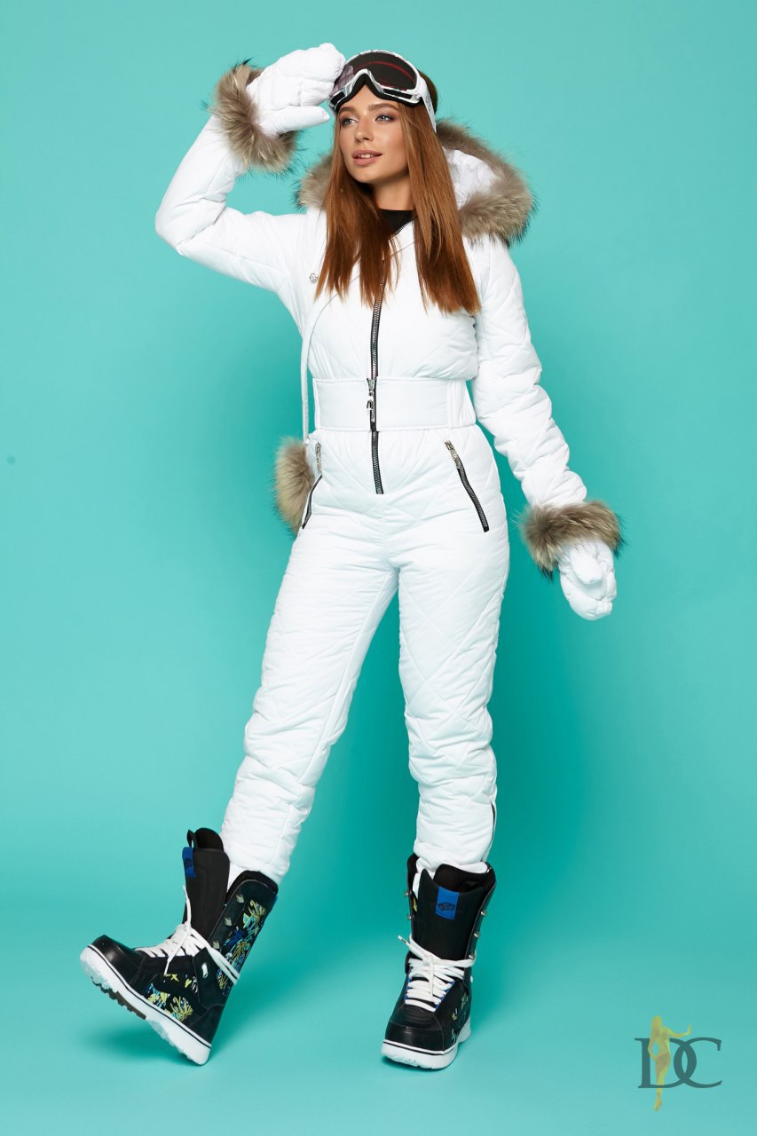 Person wearing a white snowsuit with fur accents on a teal background