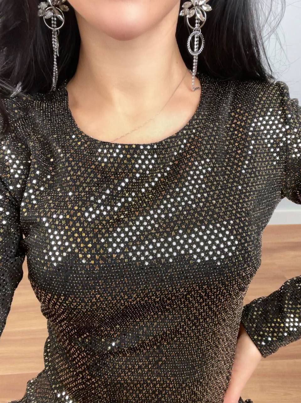Close-up of a person wearing a black sequin dress with long sleeves.