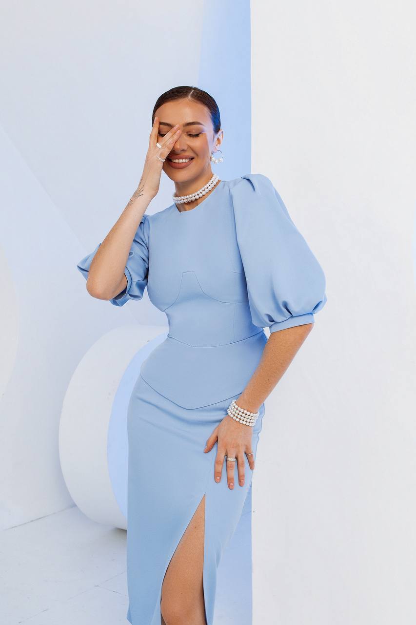 Woman wearing a light blue dress with puffed sleeves against a white background