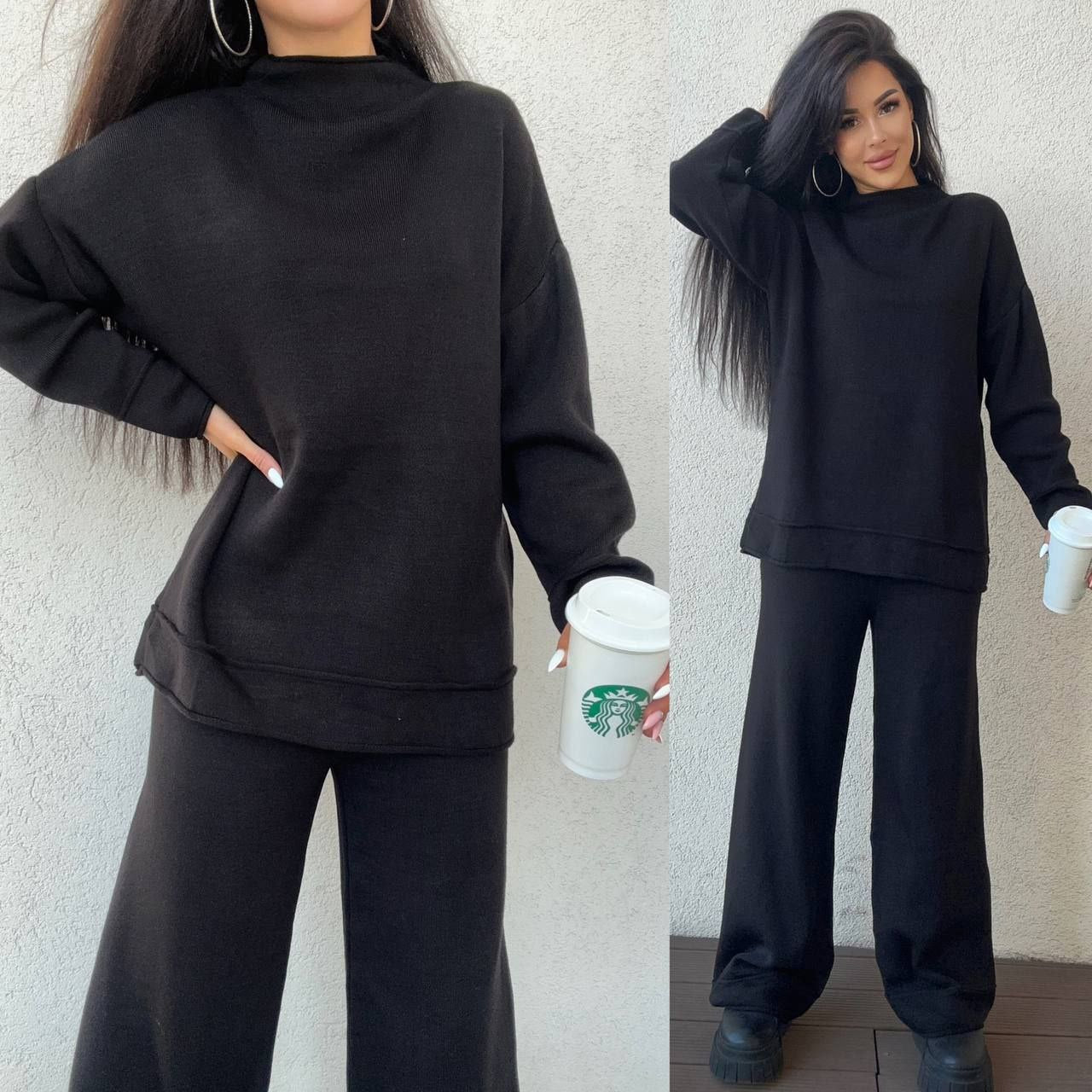 Woman wearing a black outfit holding a Starbucks cup against a neutral background