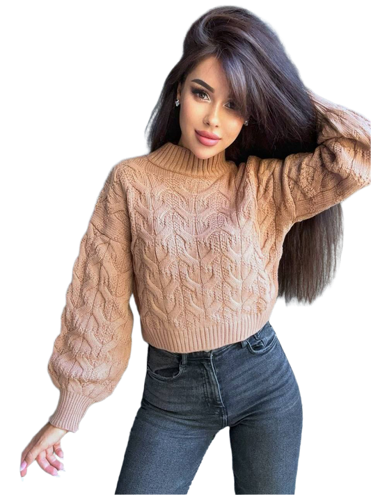 Woman wearing a beige cable knit sweater and blue jeans on a white background