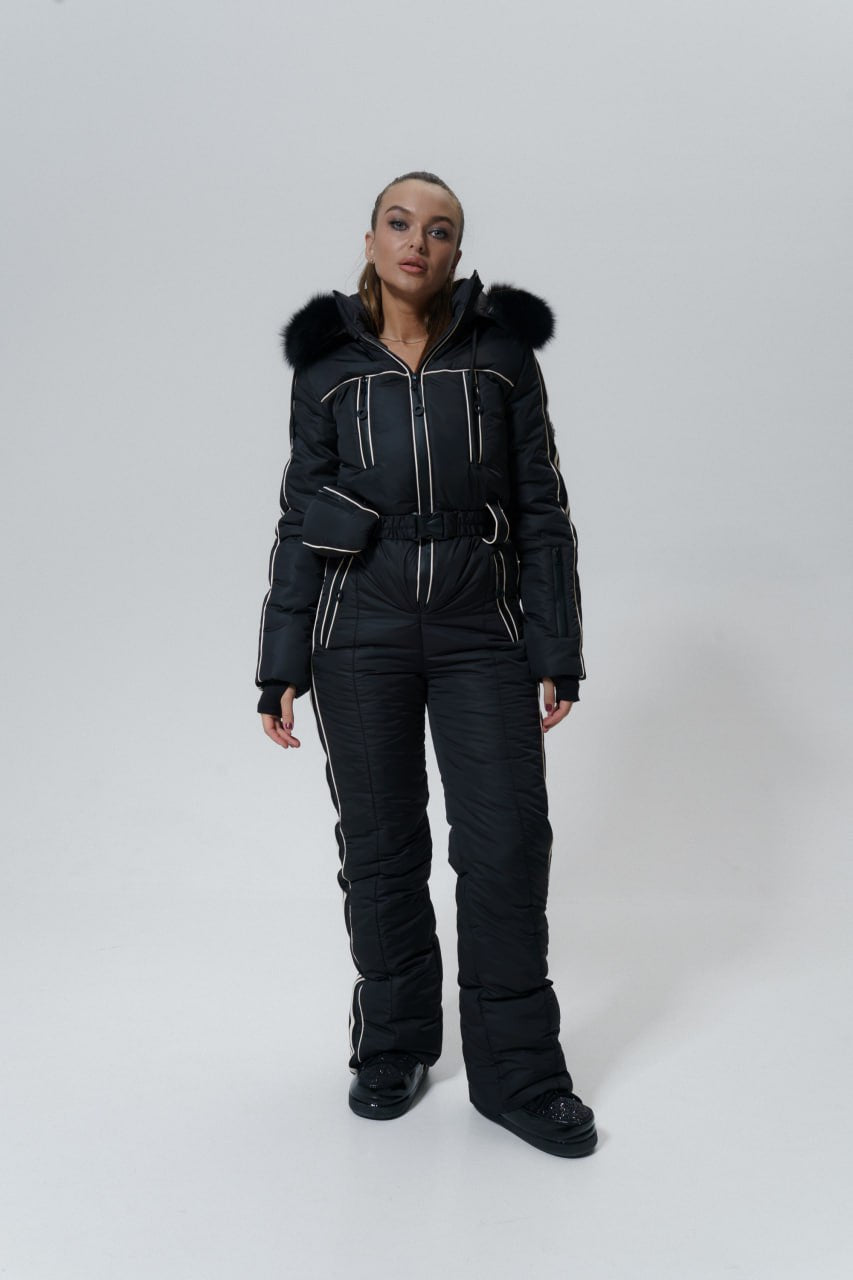Person wearing a black snowsuit with fur-lined hood on a white background