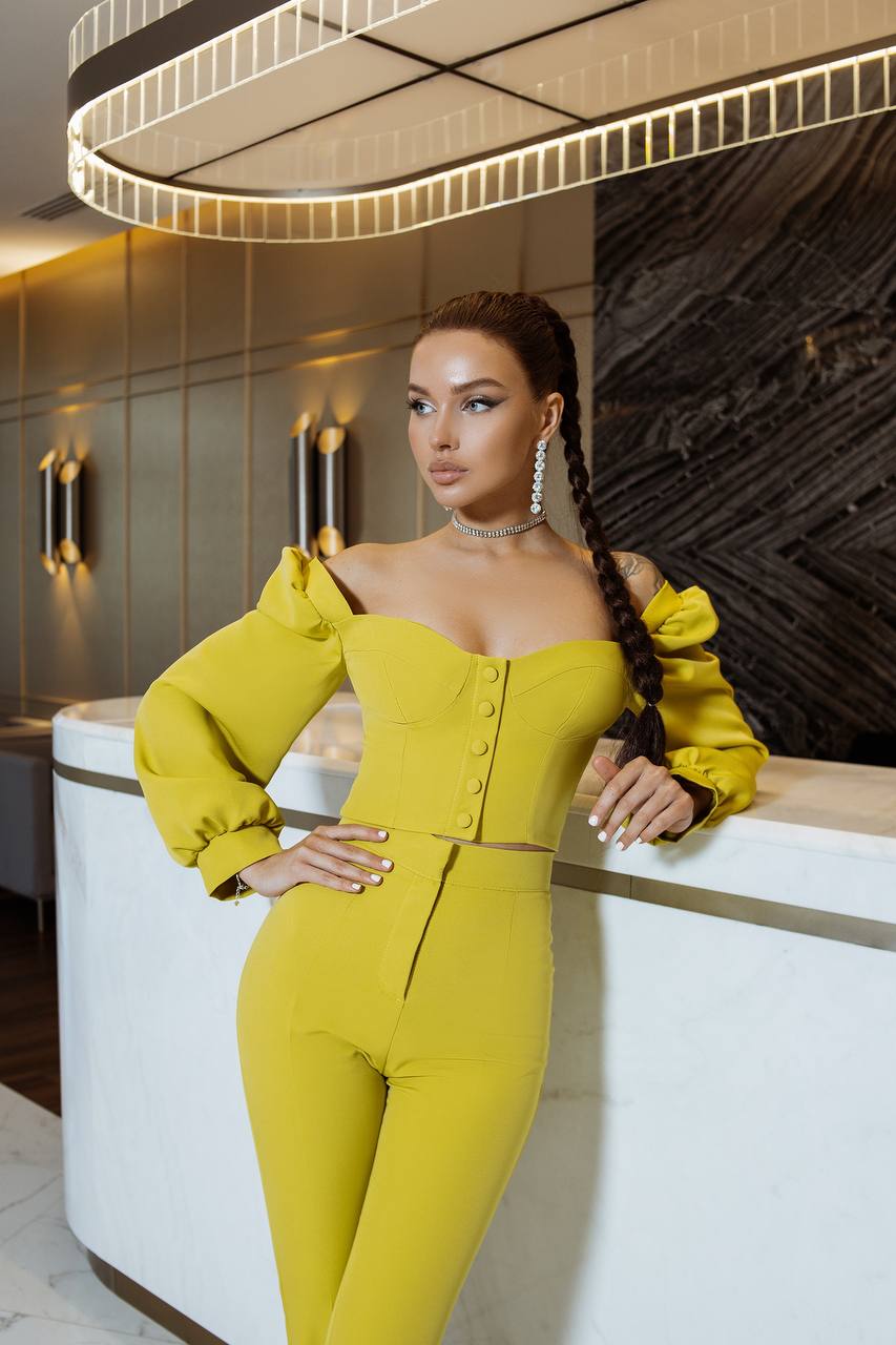 Woman in a yellow outfit posing in an elegant interior setting