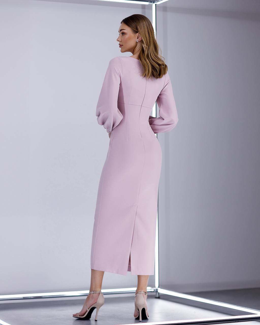 Woman wearing a pink dress with a high slit in a minimalistic setting