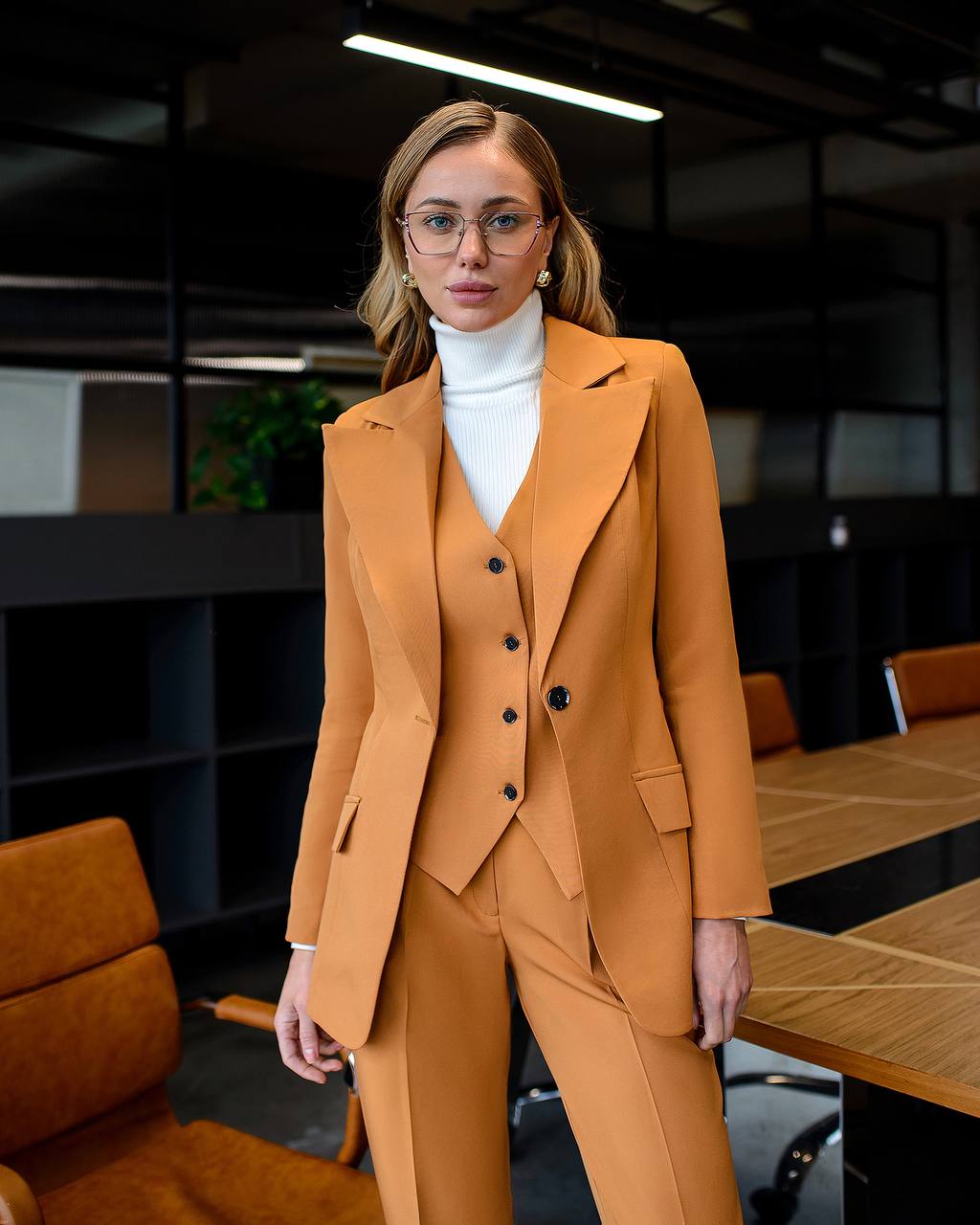 Woman in a mustard yellow suit standing in an office setting