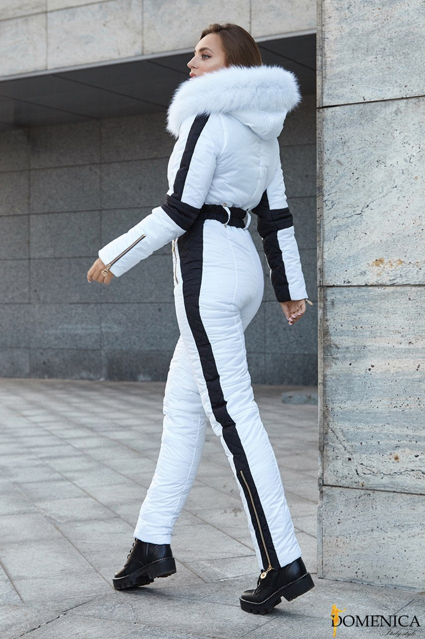 Woman in a white and black outfit with fur trim walking outdoors.