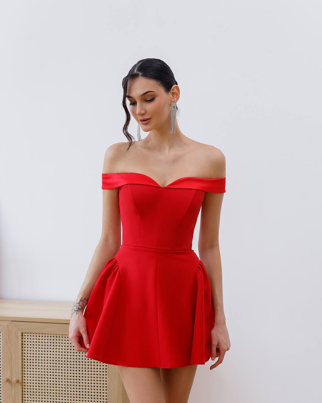 Woman wearing a red off-shoulder dress against a white background