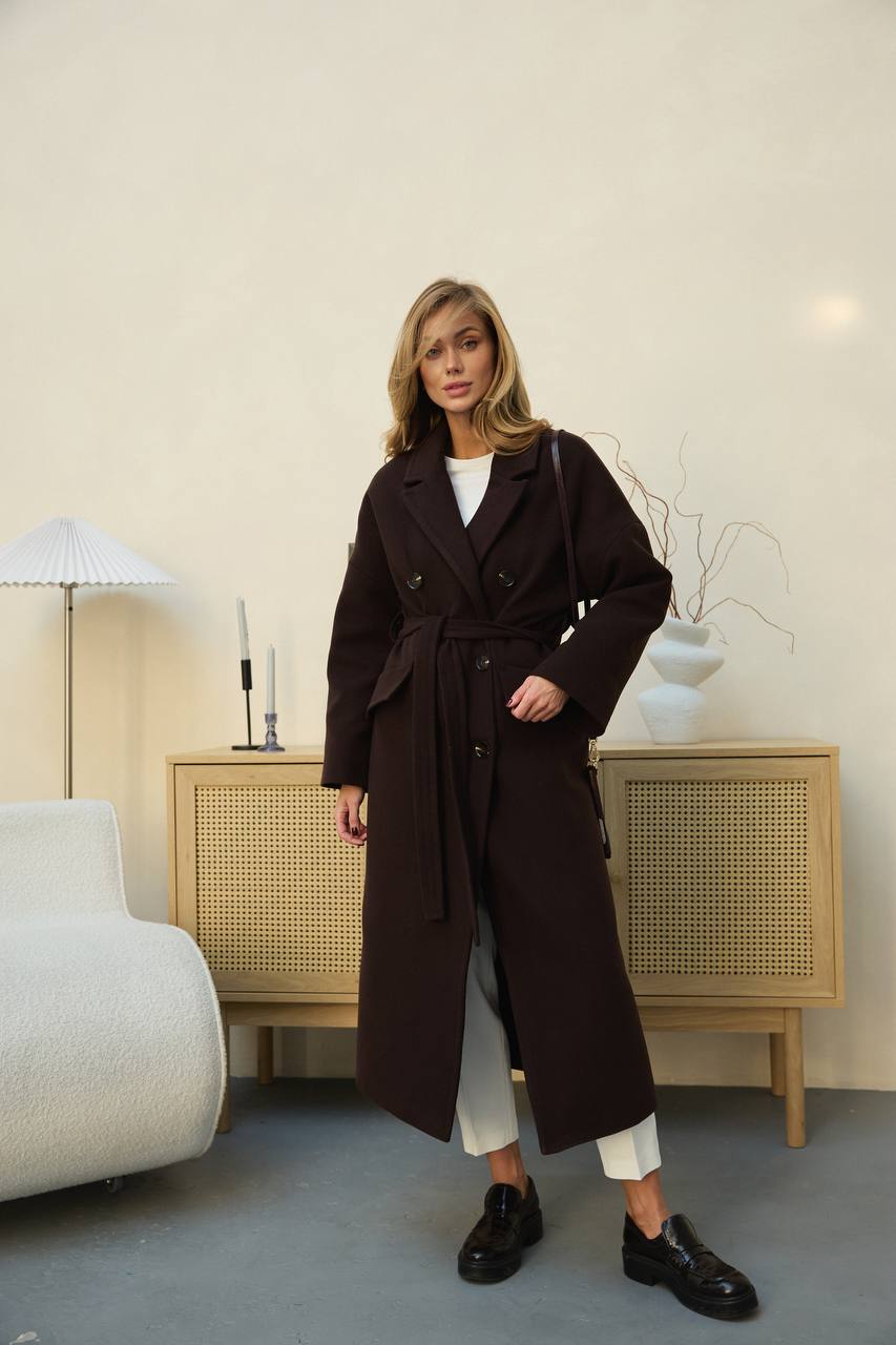 Woman wearing a long dark coat in a living room setting