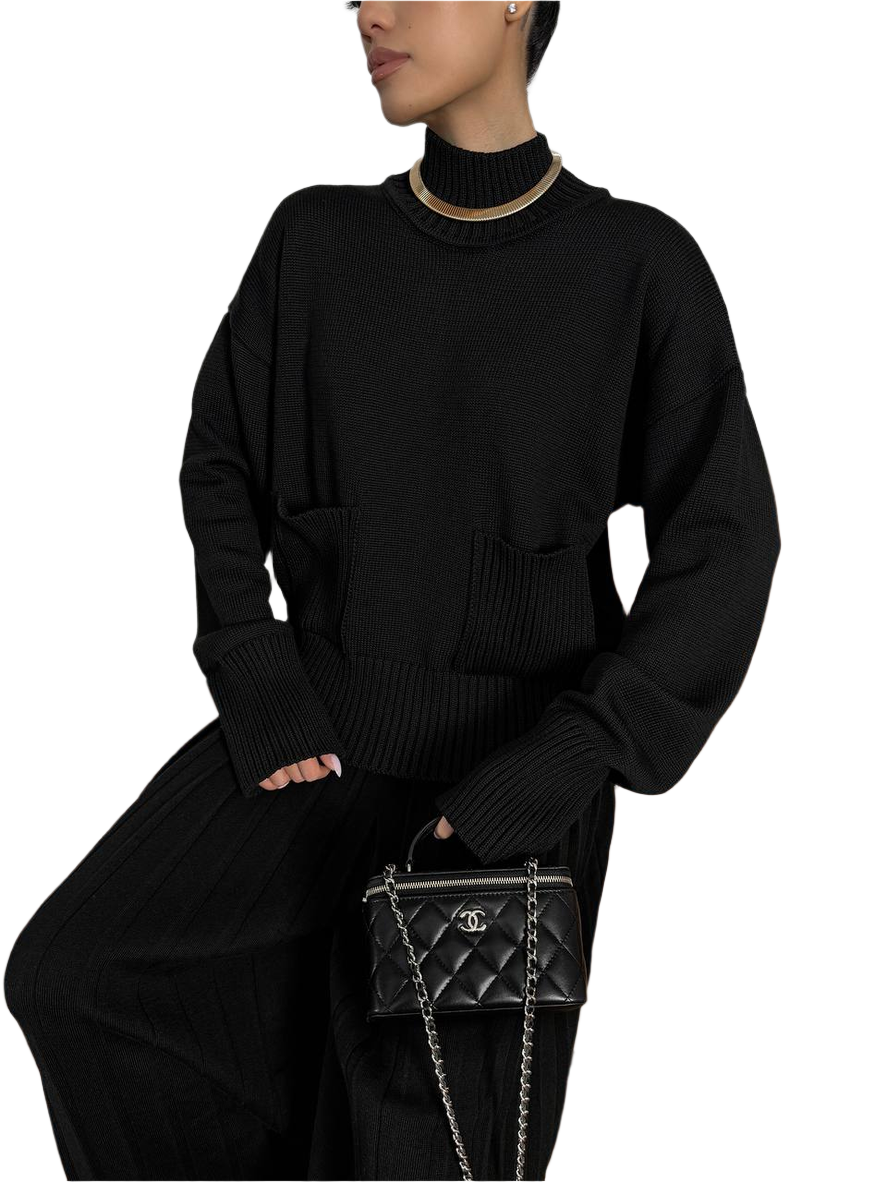 Person wearing a black outfit with a Chanel handbag on a white background