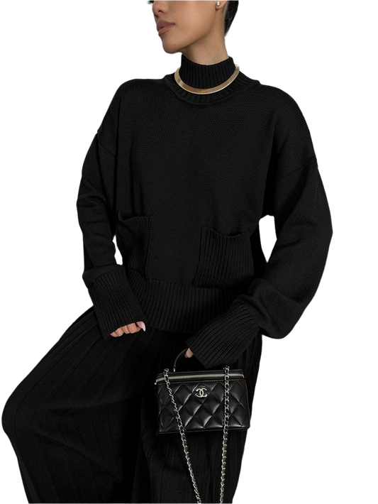 Person wearing a black outfit with a Chanel handbag on a white background