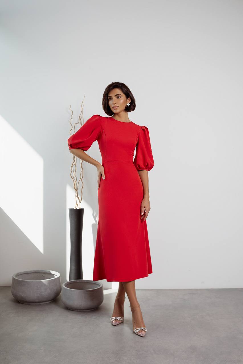 Woman wearing a red dress with puff sleeves in an indoor setting.