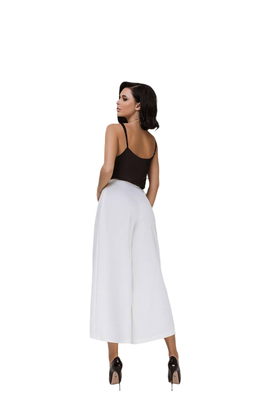 Woman wearing a black top and white wide-leg pants on a white background