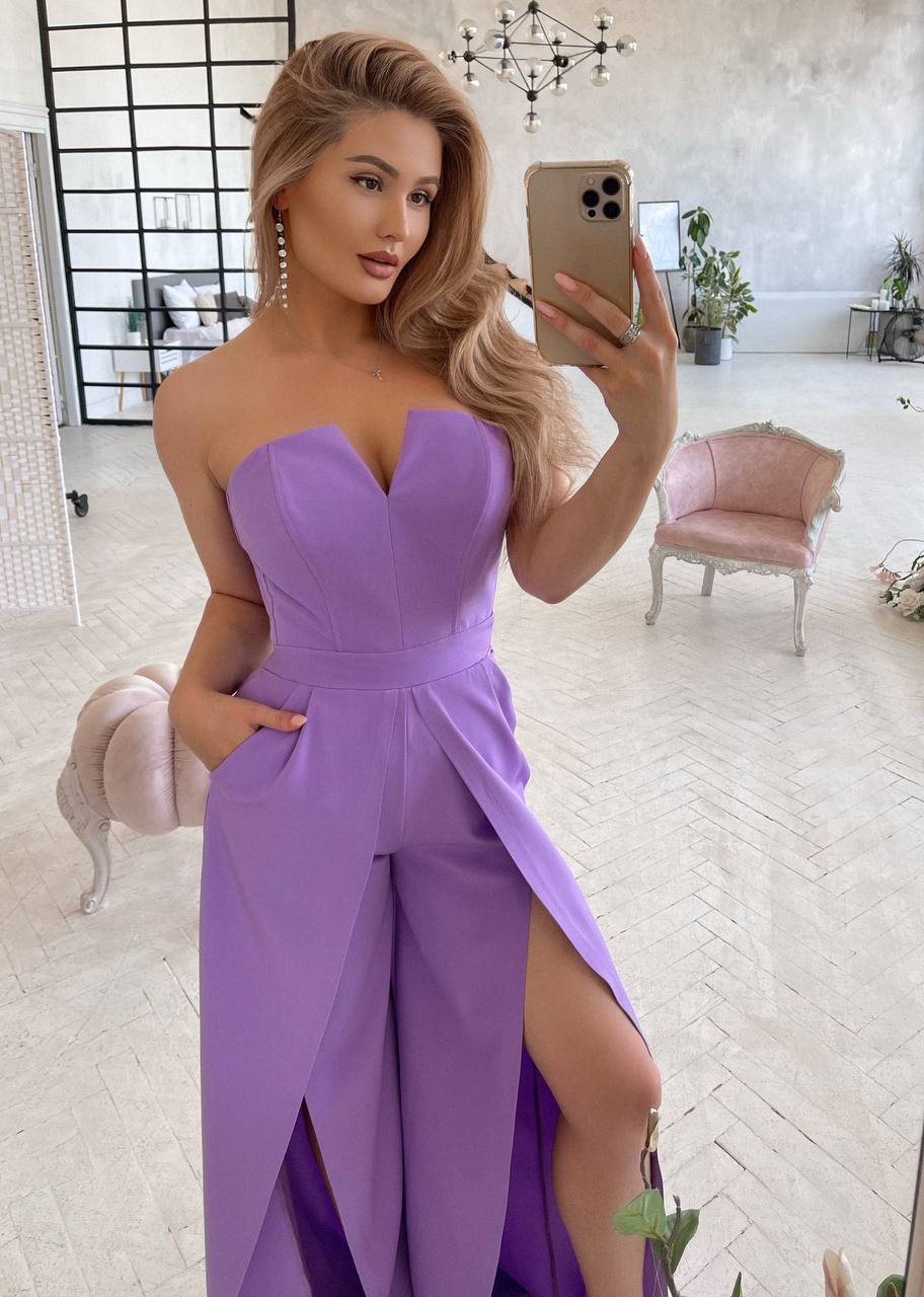 Woman taking a mirror selfie wearing a strapless purple dress in a stylish room.