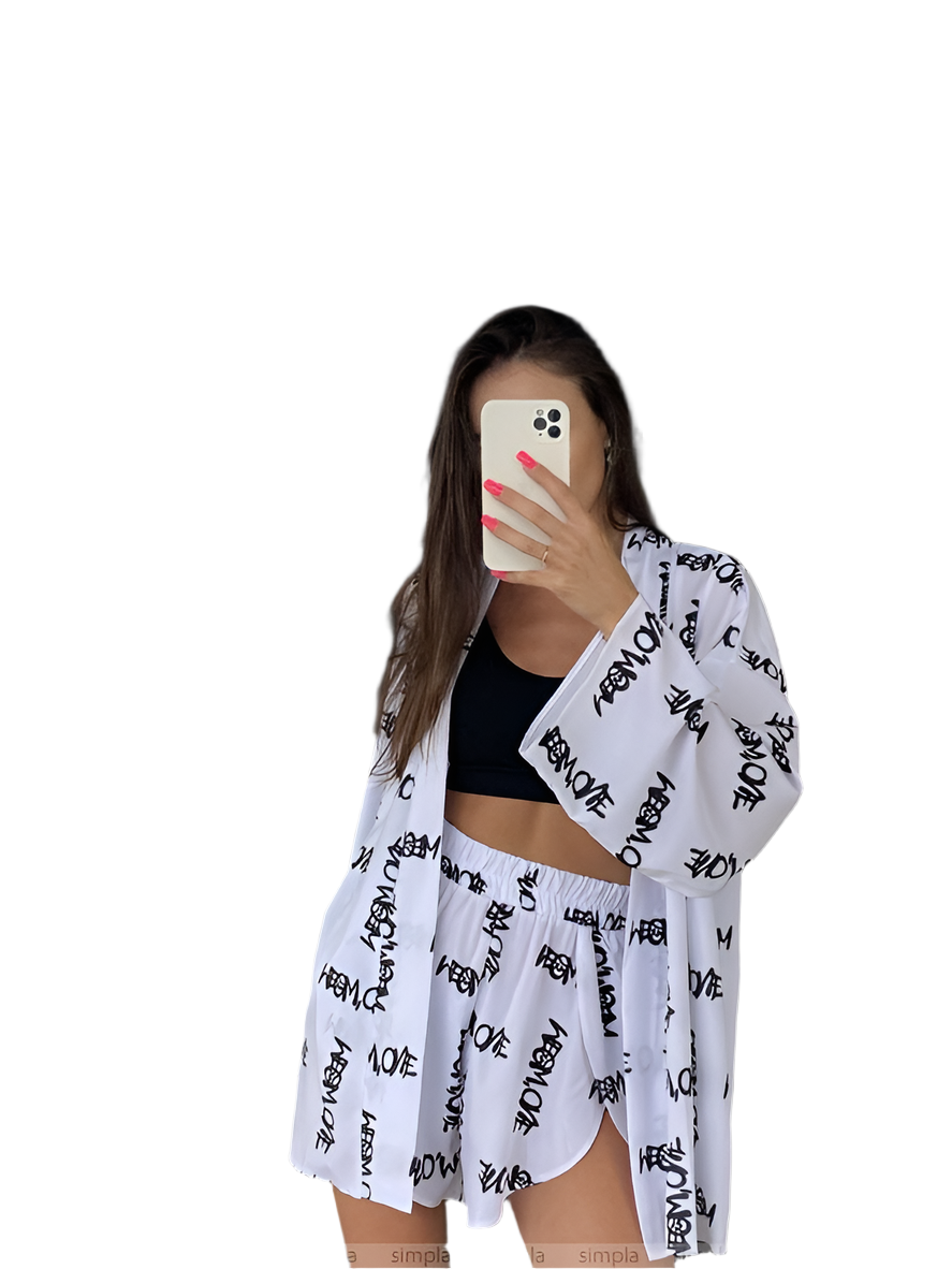 Woman wearing a white kimono with black text over a black top and shorts on a white background