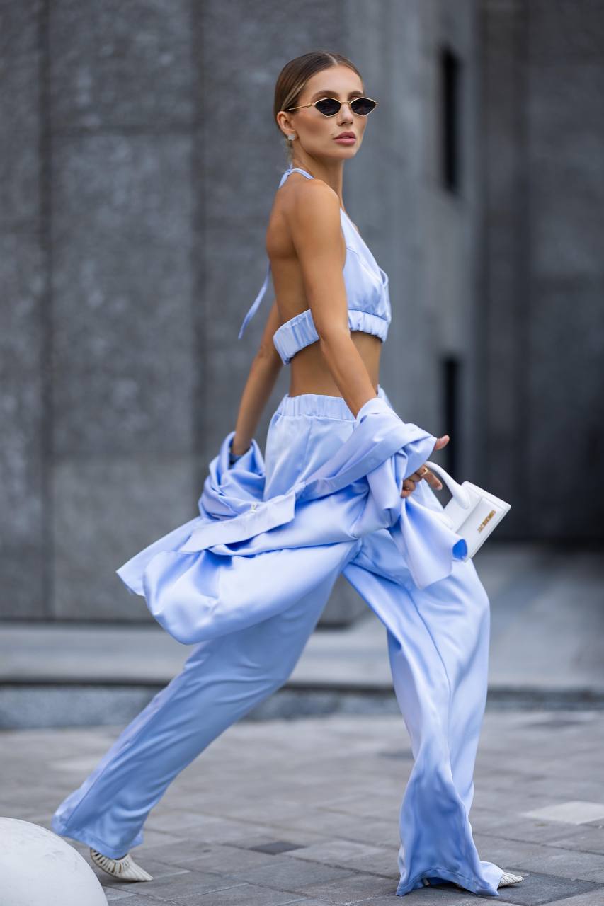 Woman in a light blue outfit walking outdoors with a blurred background