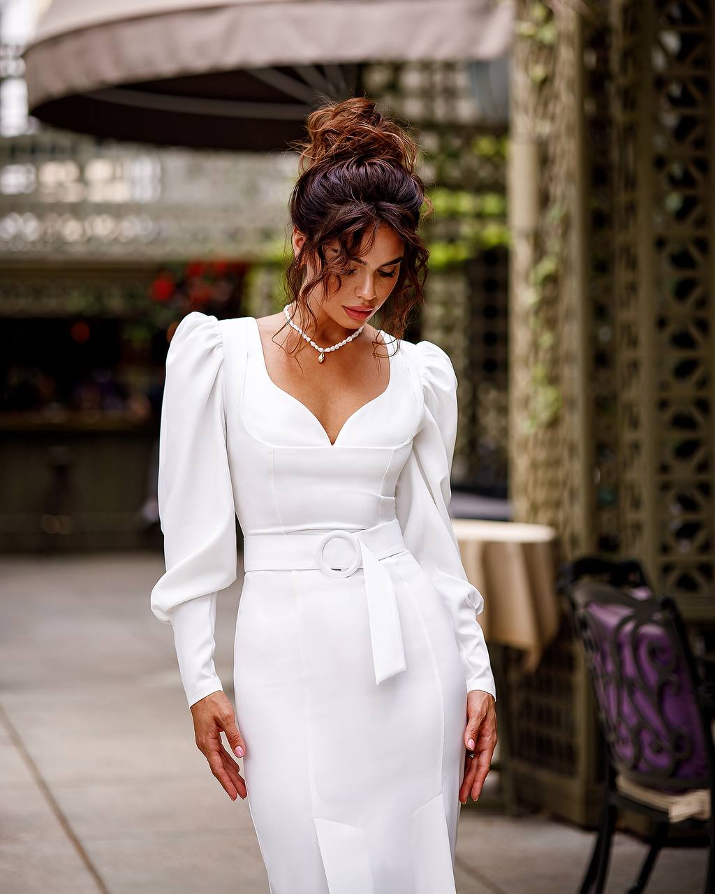 Woman in a white dress standing outdoors with blurred background