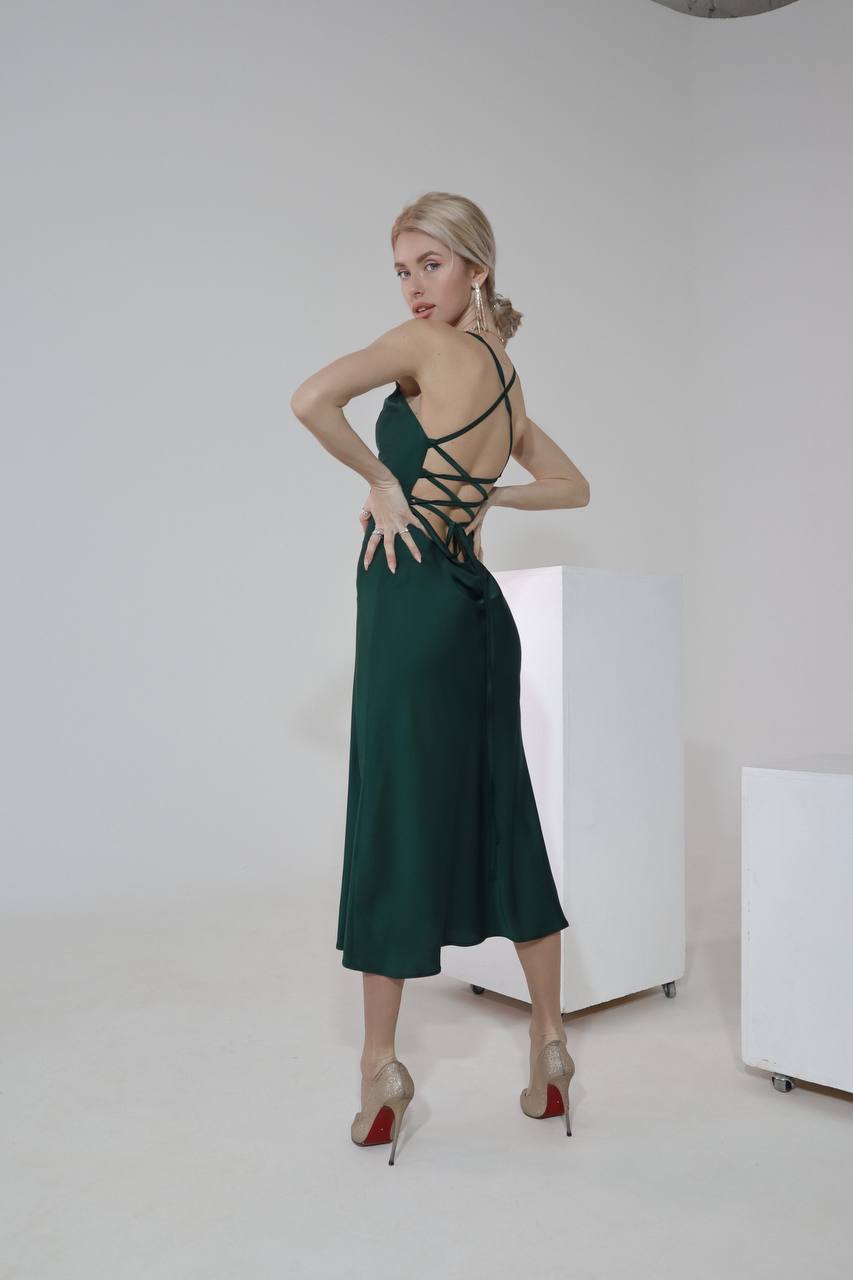 Woman wearing a green dress with strappy details in a minimalistic setting