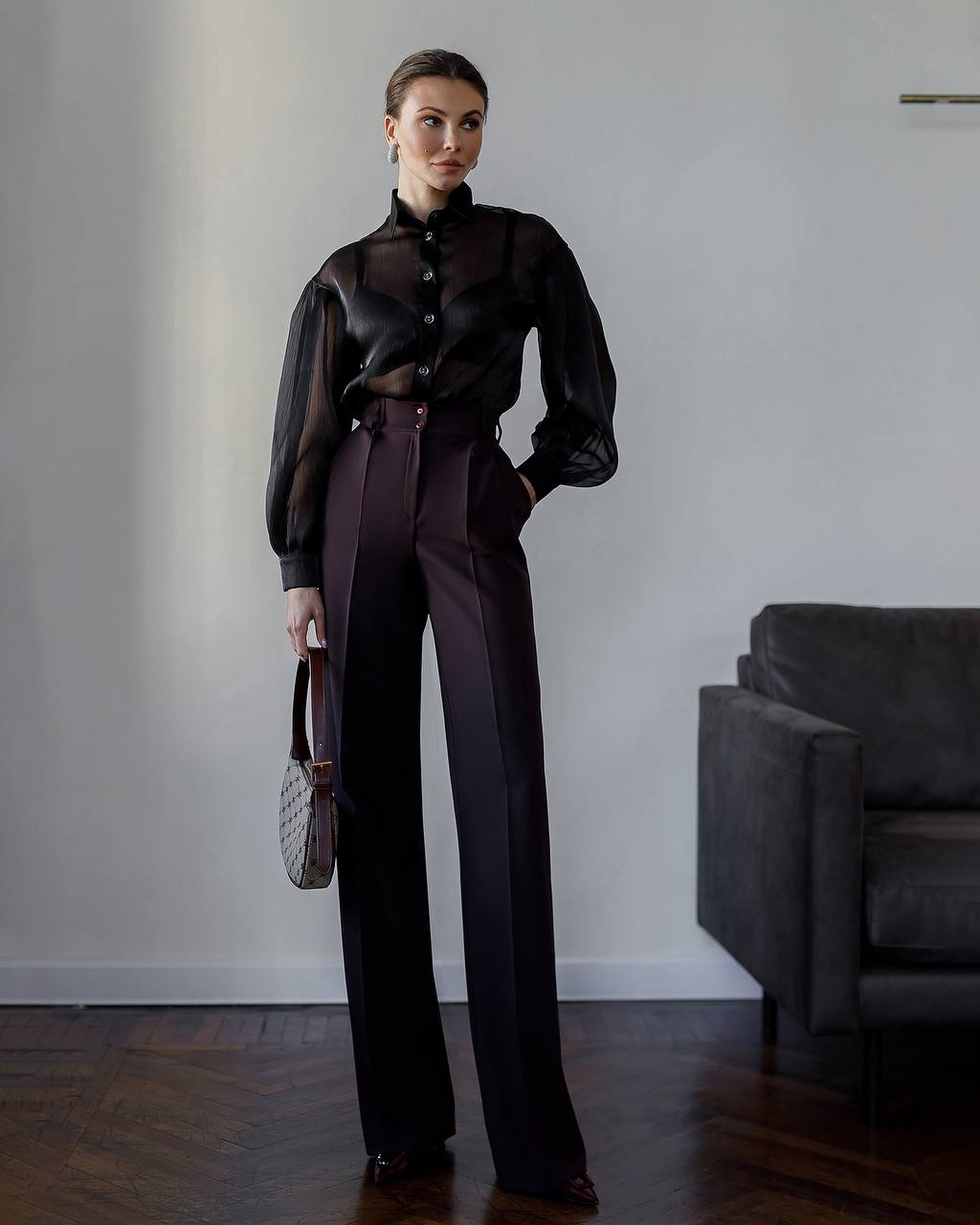 Woman wearing a black blouse and dark pants in an indoor setting.