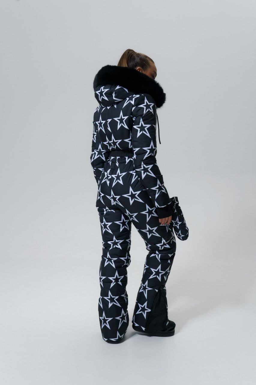 Person wearing a star-patterned onesie with fur-lined hood on a white background