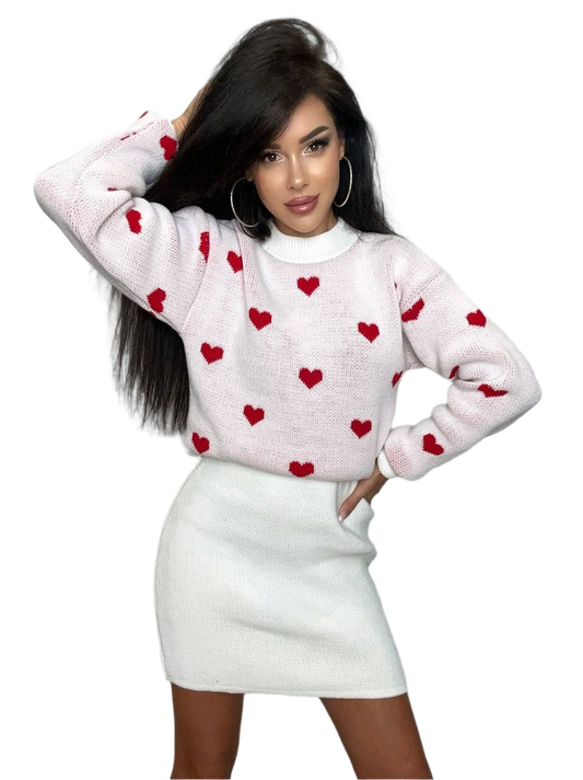 Woman wearing a white sweater with red heart patterns and a white skirt on a white background