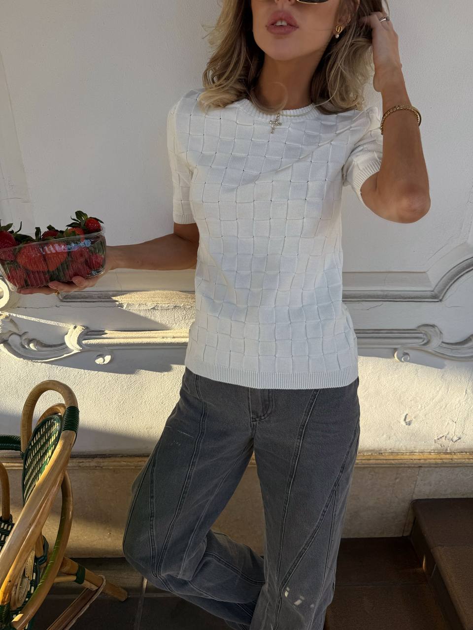 Woman wearing a light blue textured sweater and dark pants in an elegant interior setting.