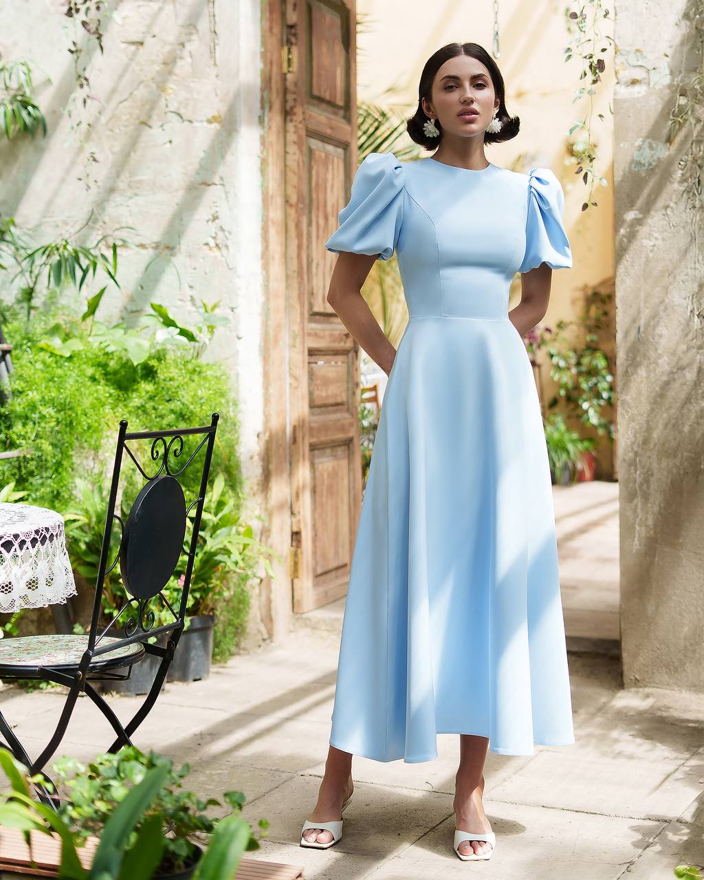 Woman in a light blue dress standing in a garden setting