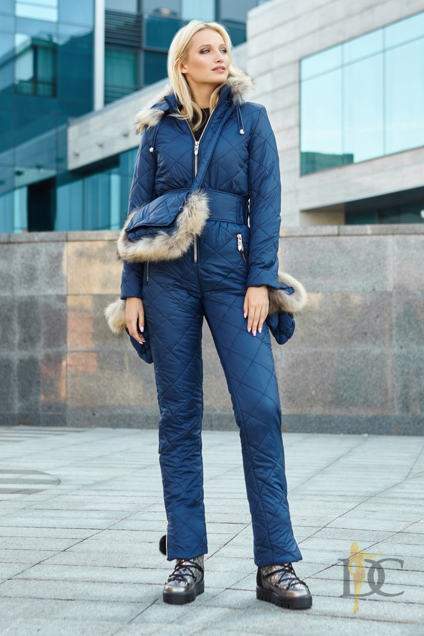 Woman wearing a blue winter jumpsuit with fur trim in an urban setting