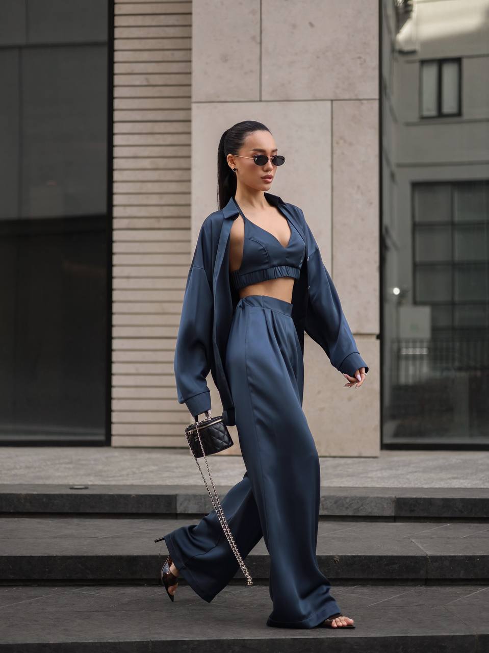 Woman in a blue outfit walking on a city street.
