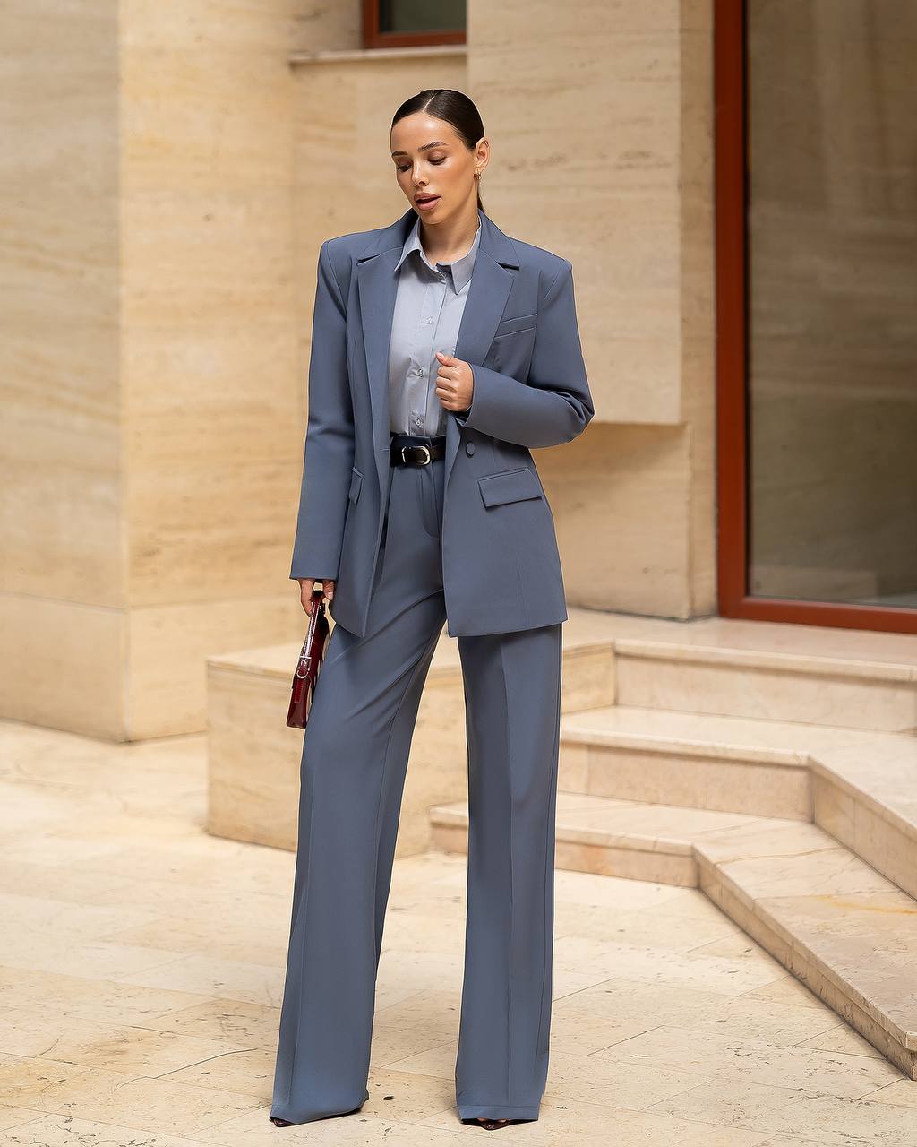 Woman in a gray suit standing outdoors with a building in the background