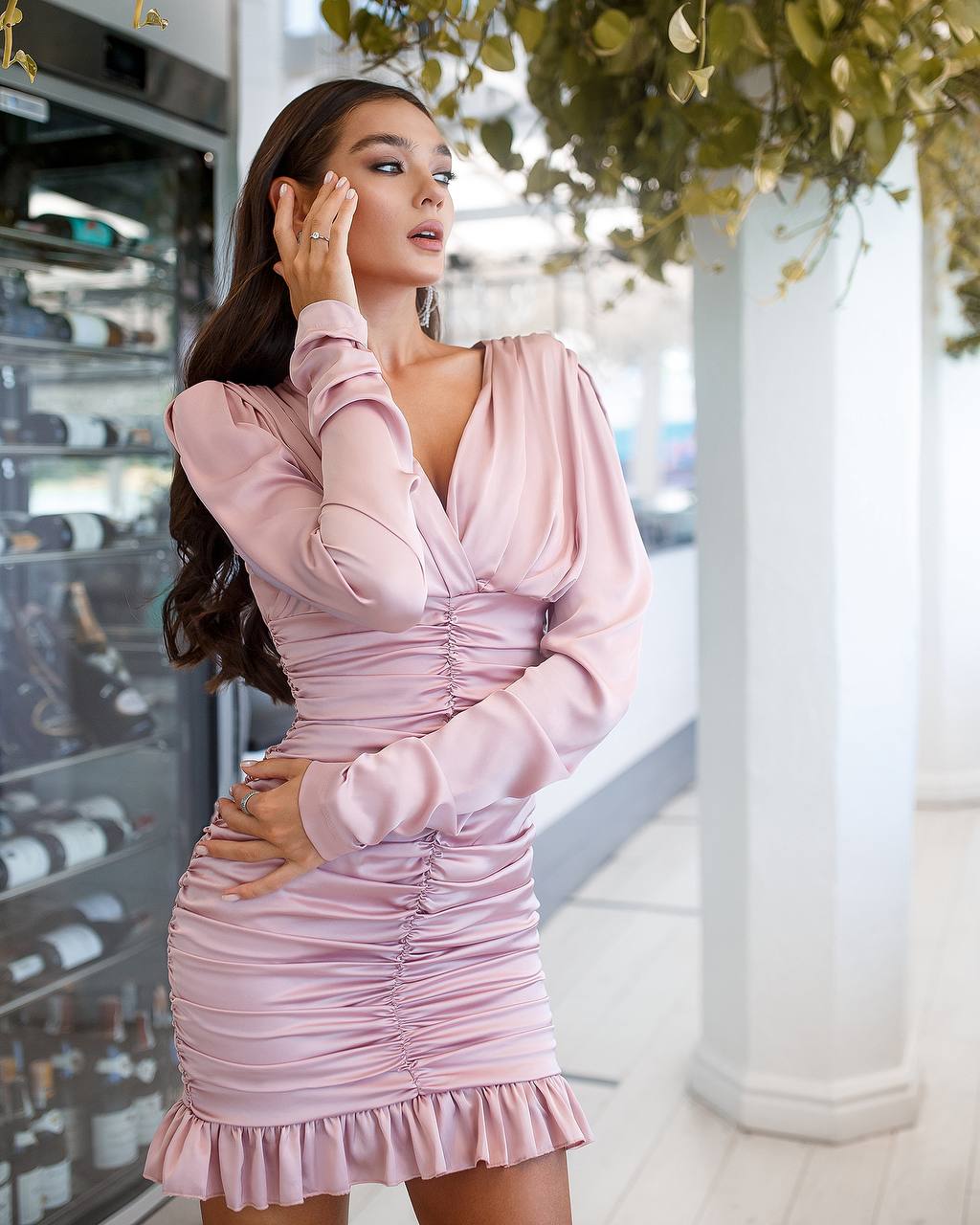 Woman wearing a pink dress in an indoor setting with decorative elements.