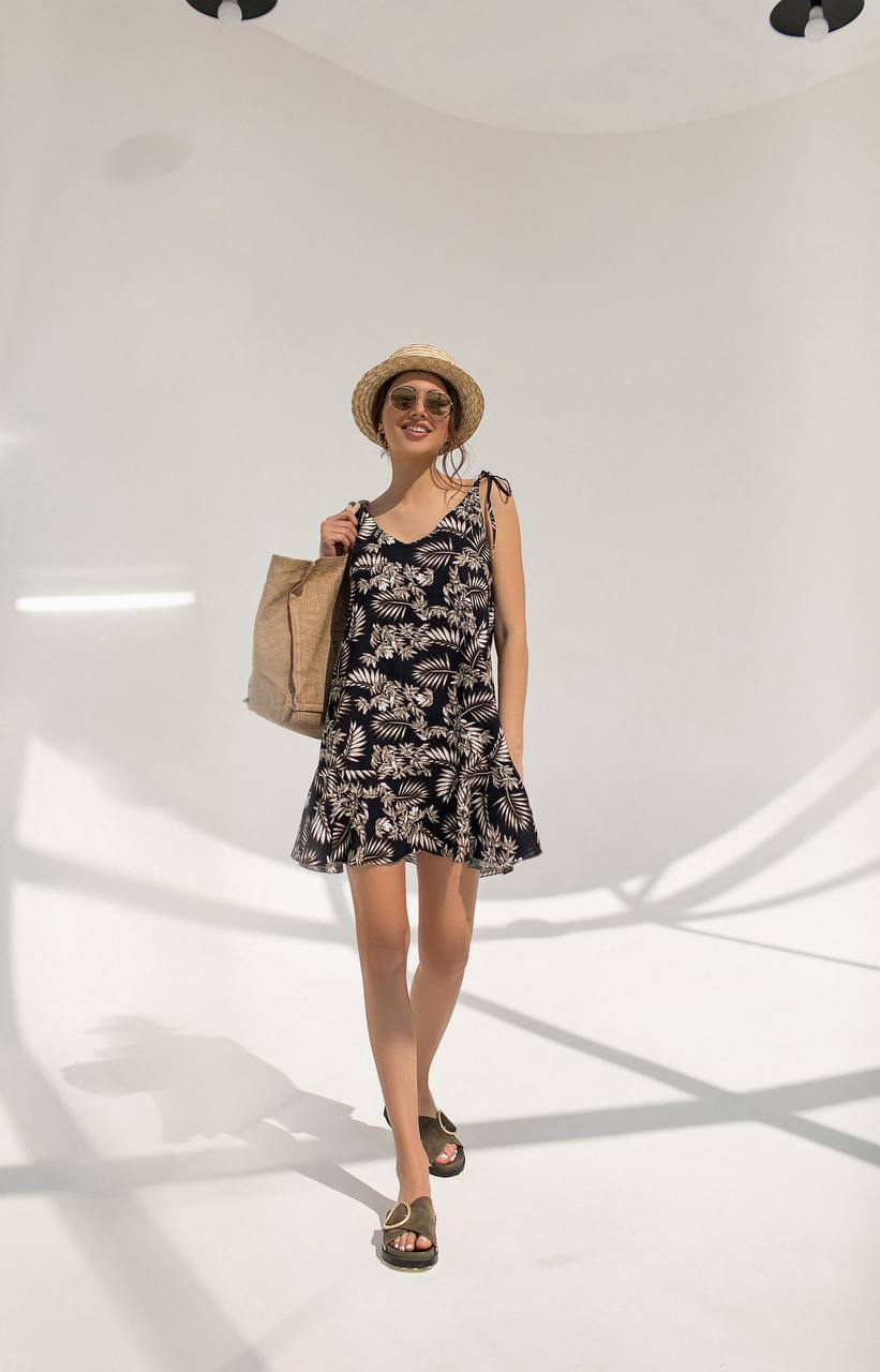 Woman wearing a floral dress and straw hat holding a bag on a white background