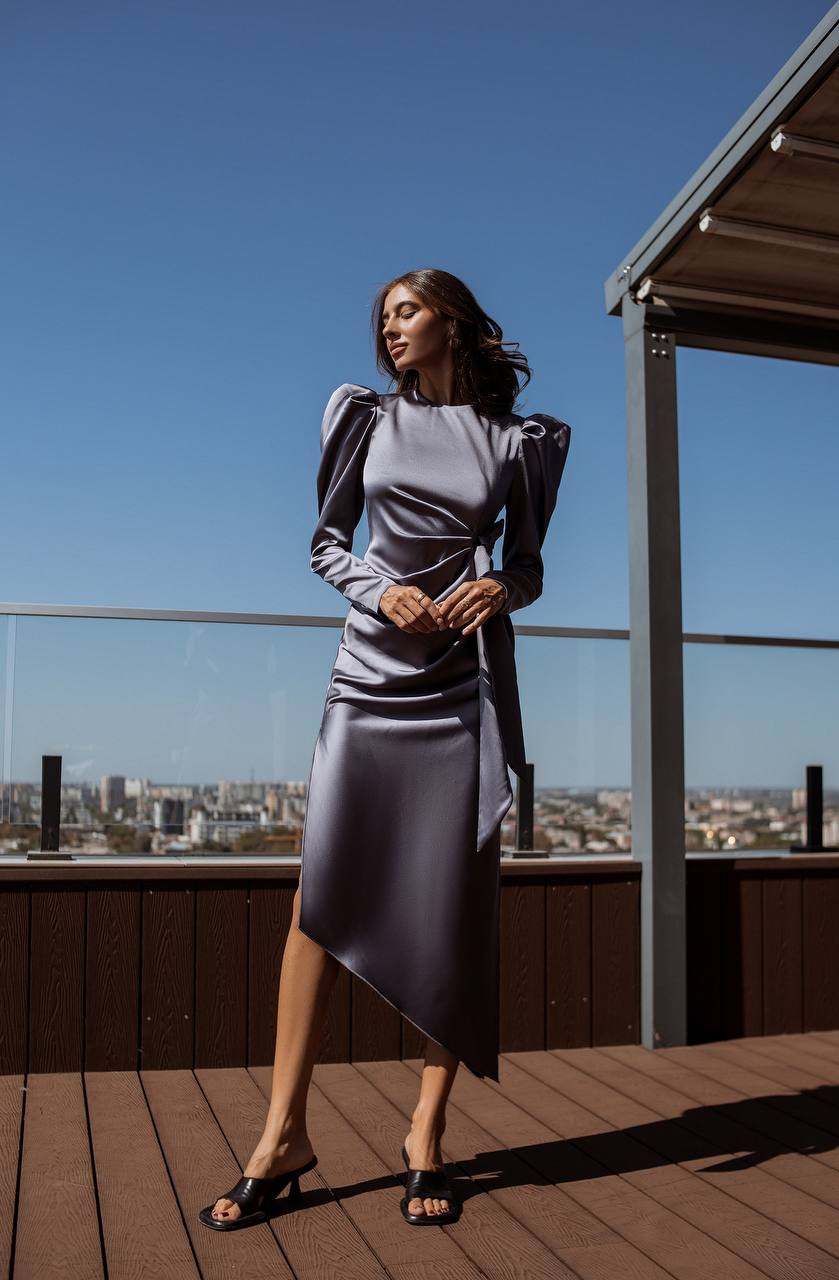 Woman in a gray dress standing on a rooftop with a cityscape view