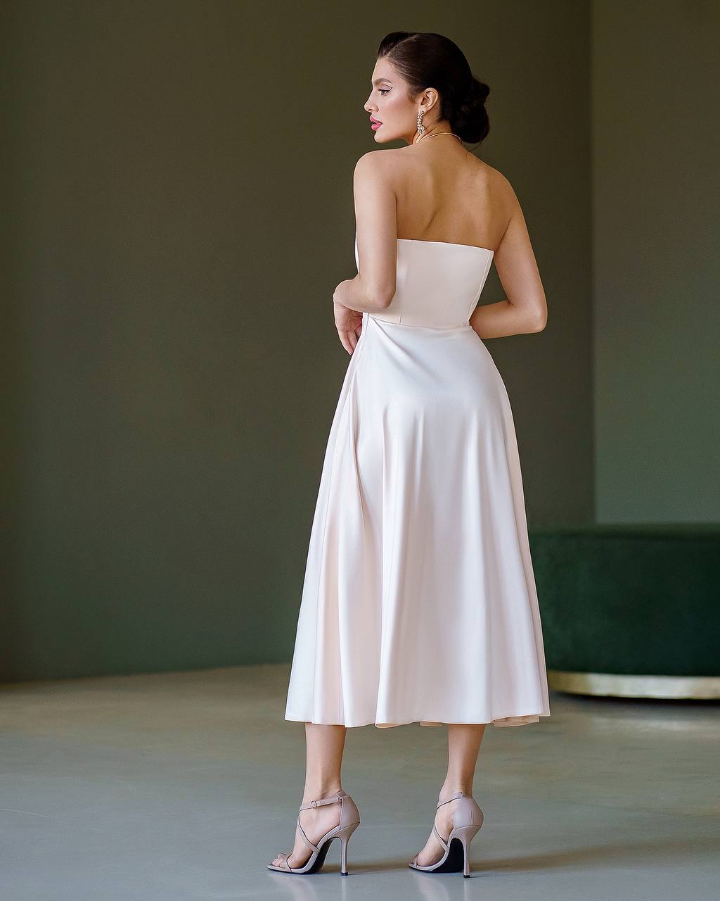 Woman wearing a strapless white dress with a plain background