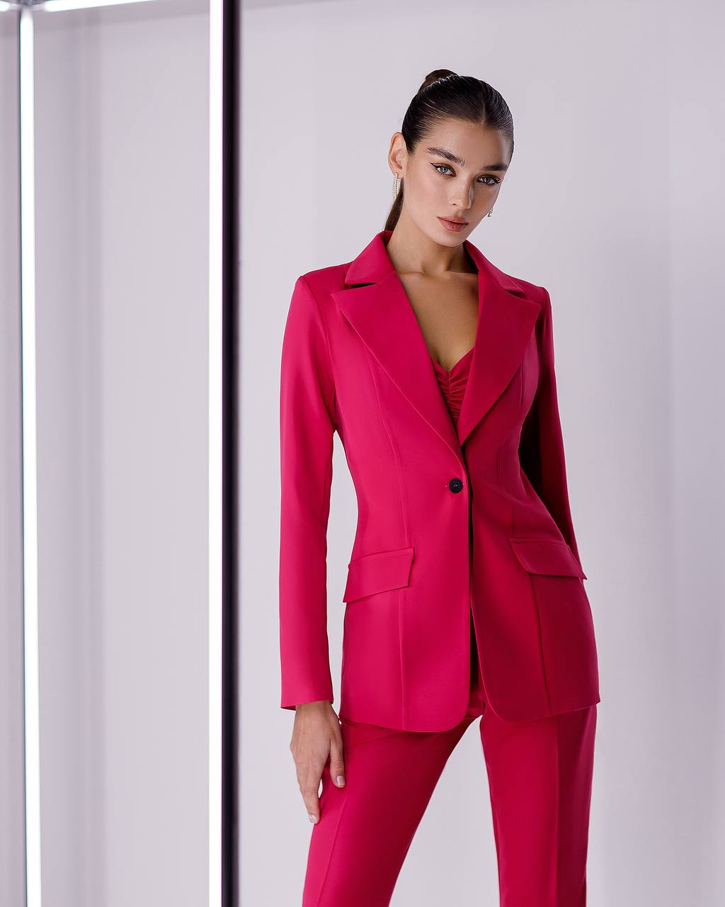 Woman wearing a bright pink suit against a white background
