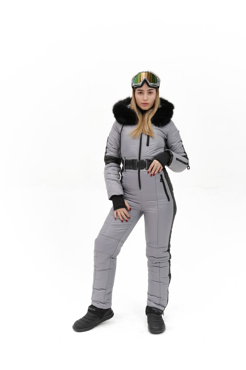 Person wearing a gray snowsuit with black fur trim on a white background