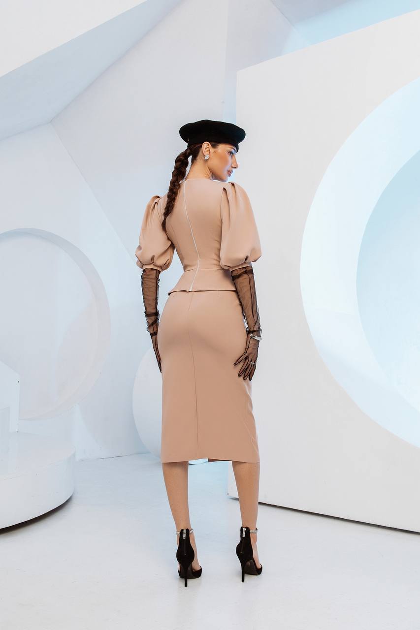 Woman in a beige dress and black hat standing against a modern, abstract white and blue background