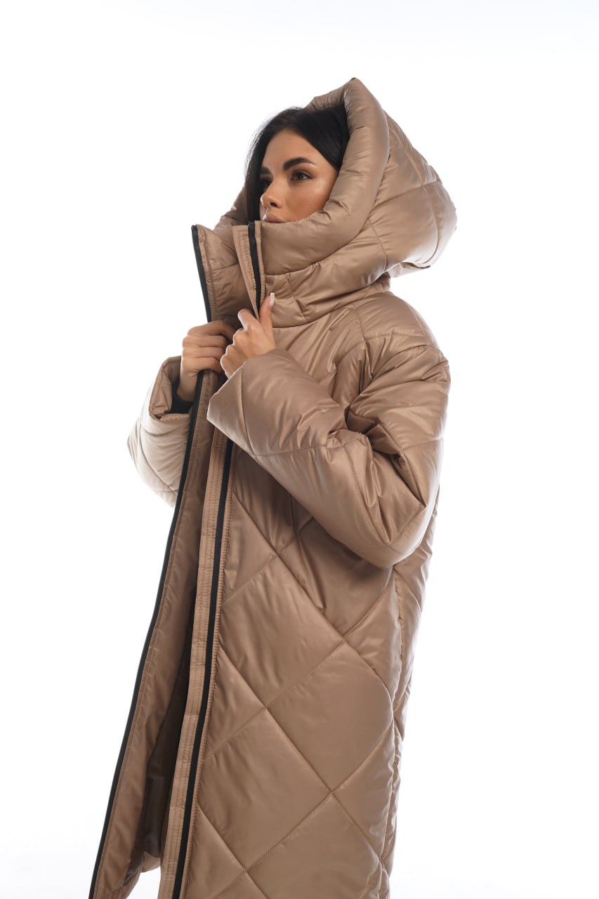 Woman wearing a beige quilted coat with a hood on a white background