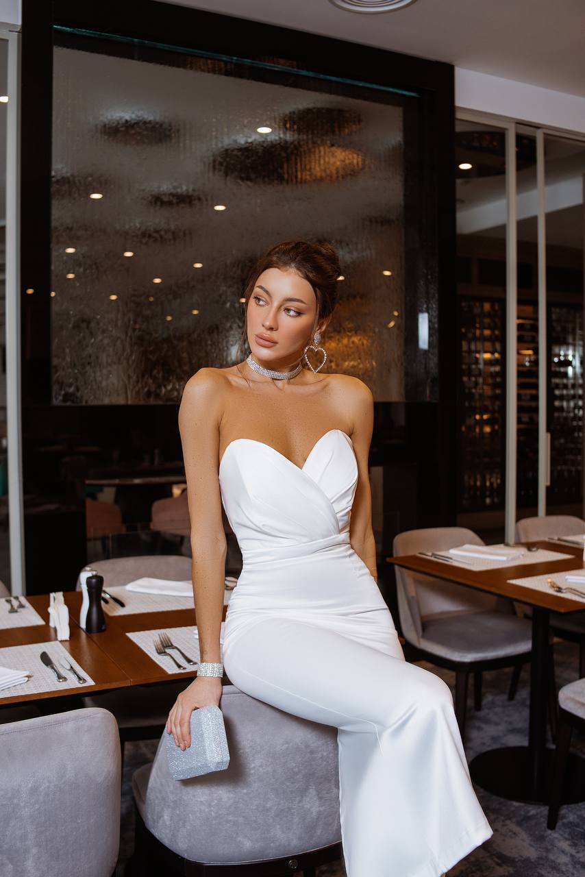 Woman in a white dress sitting at a restaurant table.