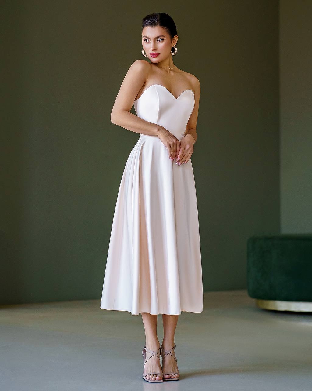 Woman wearing a strapless white dress against a plain background