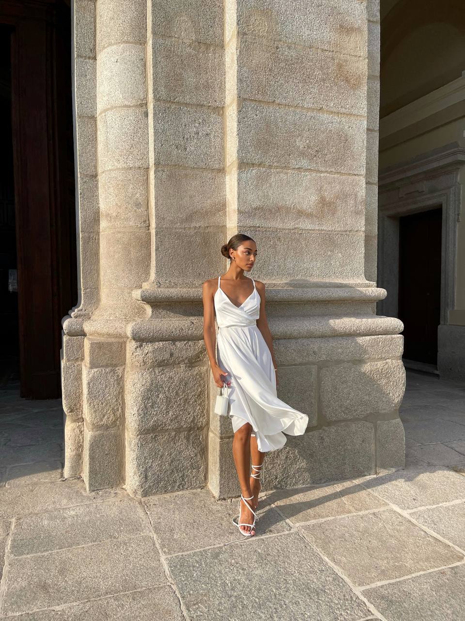 Woman in a white dress standing against a stone wall