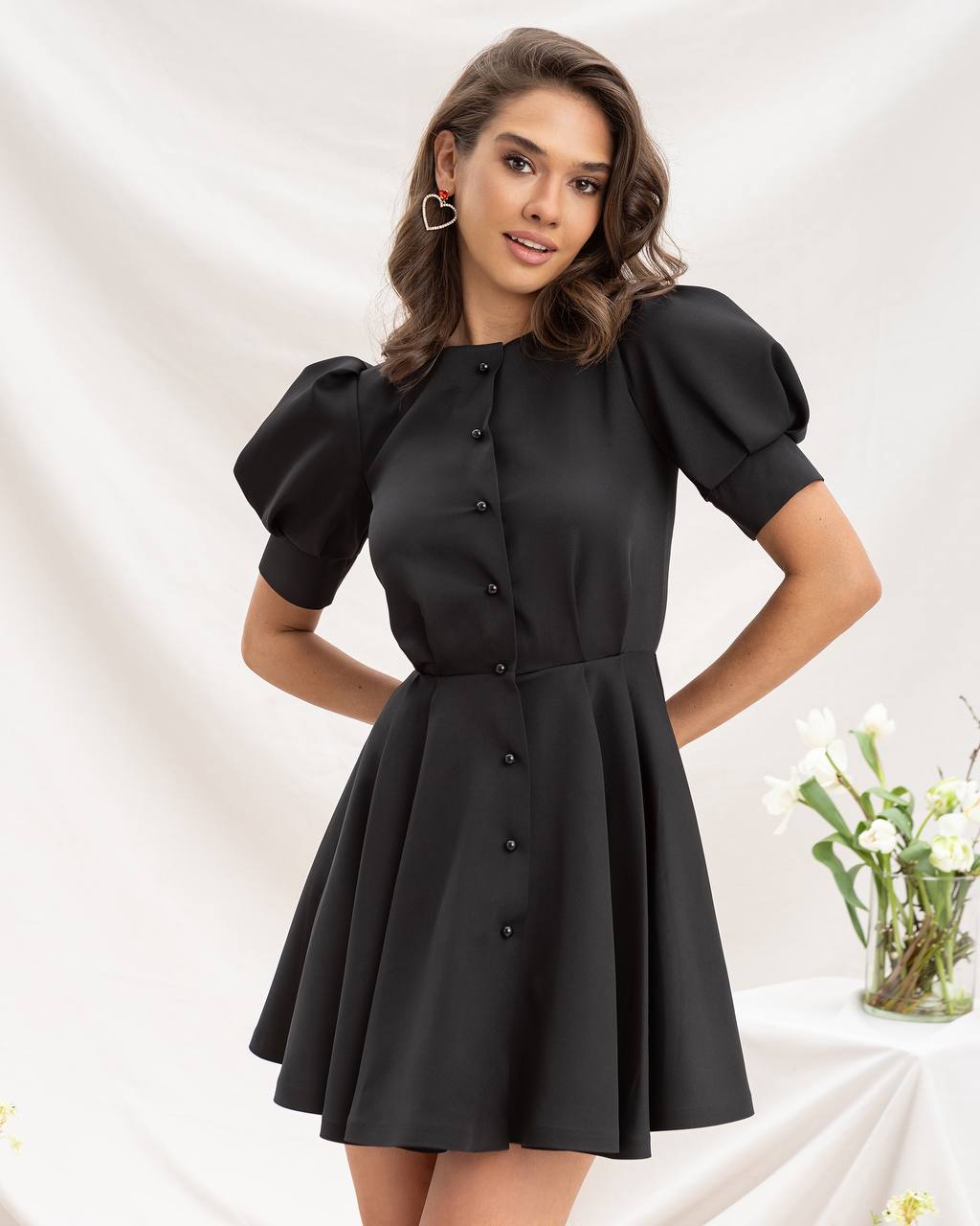 Woman wearing a black dress with puff sleeves on a white background