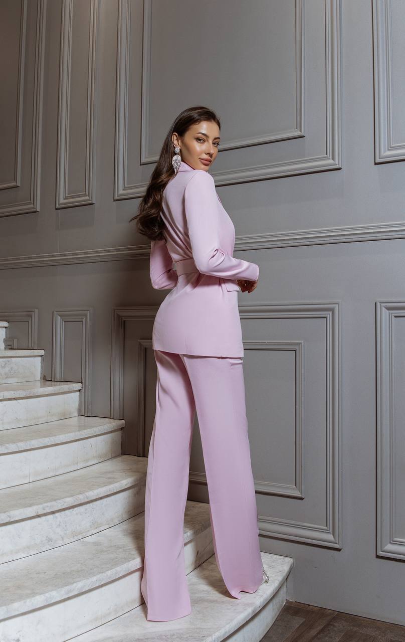 Woman in a pink outfit standing on a staircase with gray paneled walls.