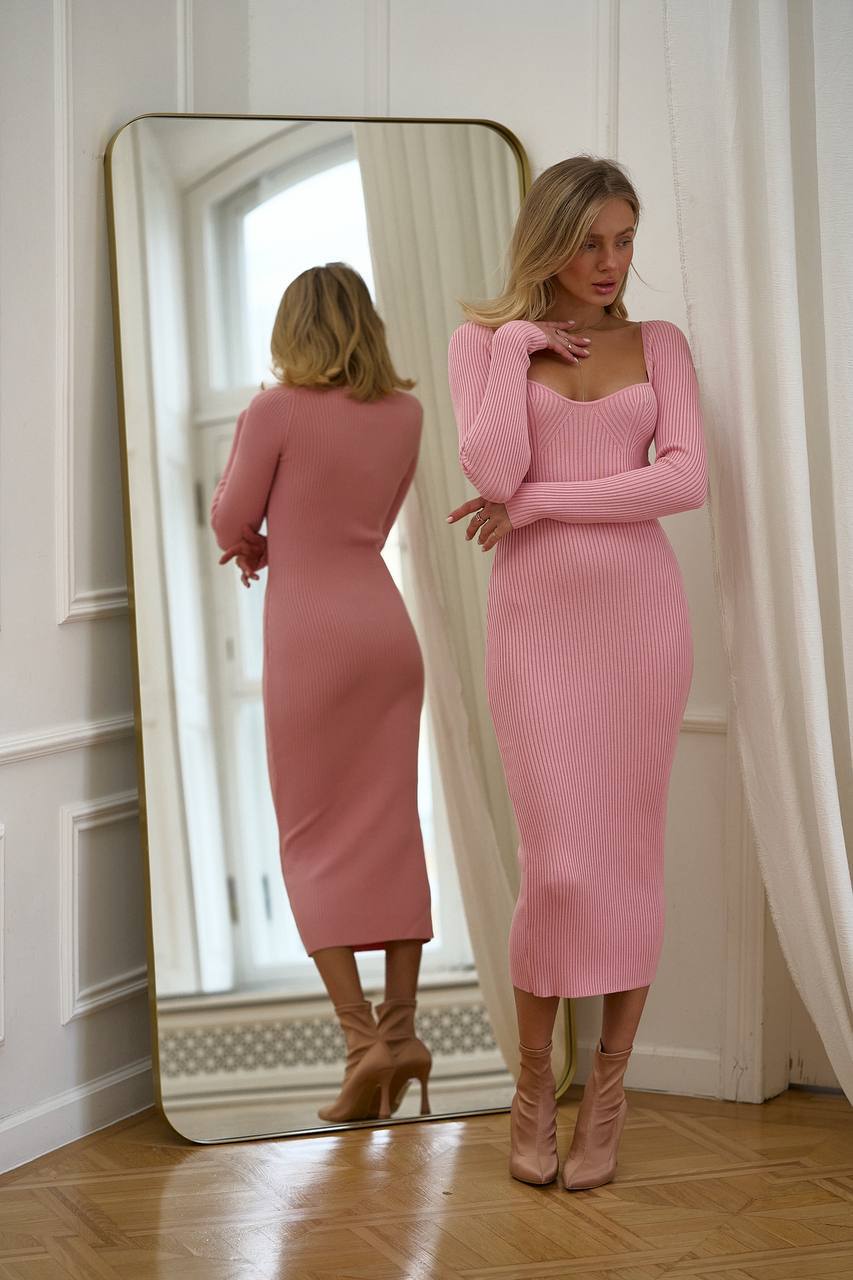 Woman in a pink dress standing in front of a mirror.