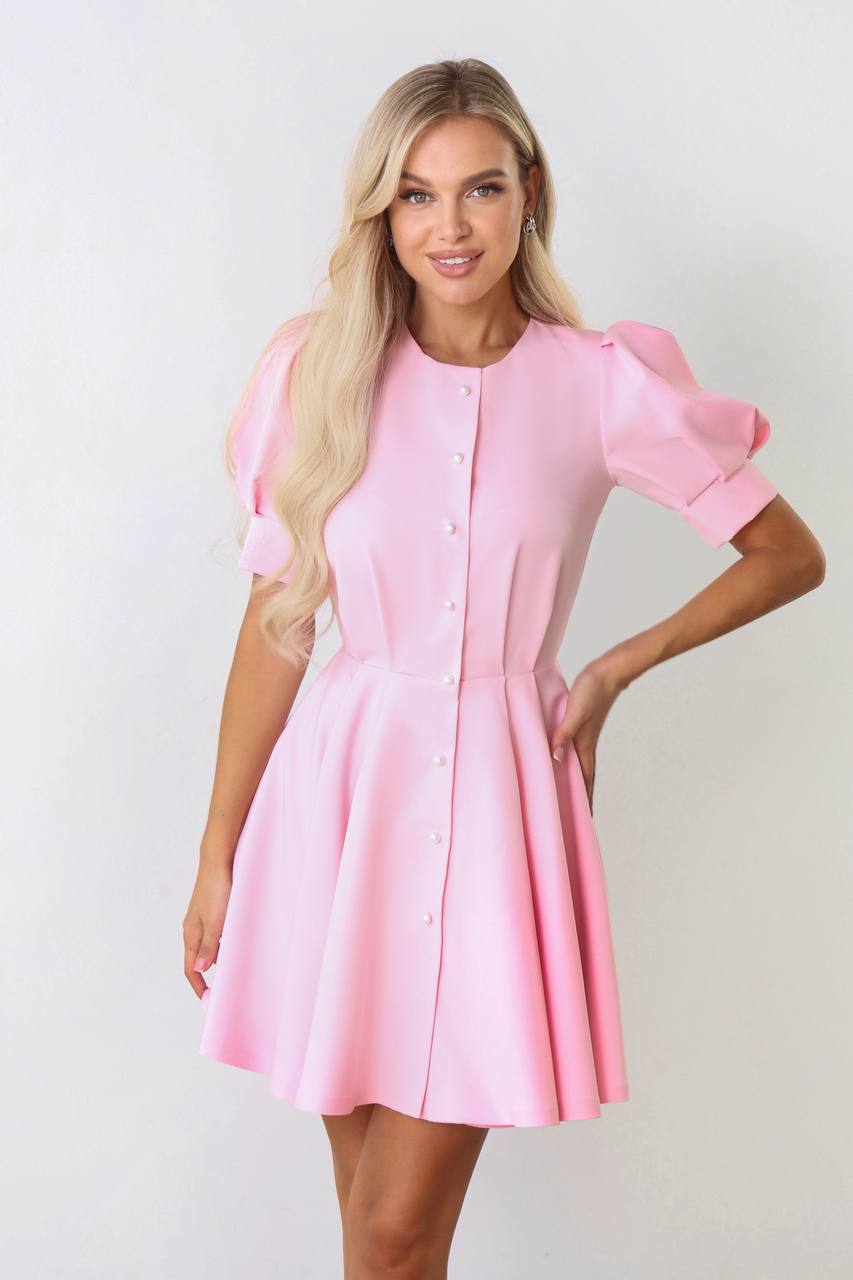 Woman wearing a pink dress with puff sleeves against a white background