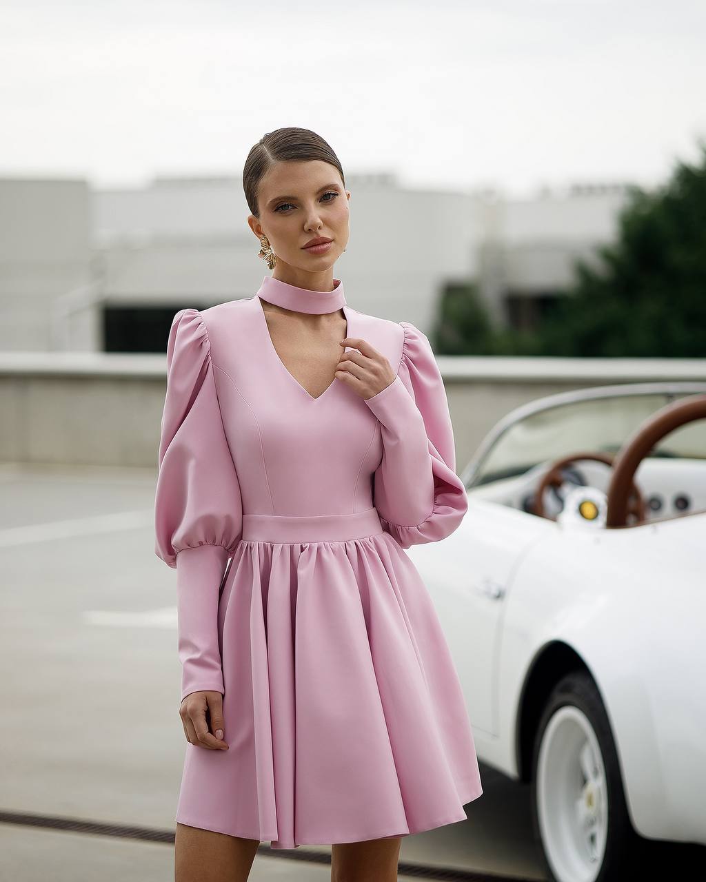 Woman in a pink dress standing next to a vintage car