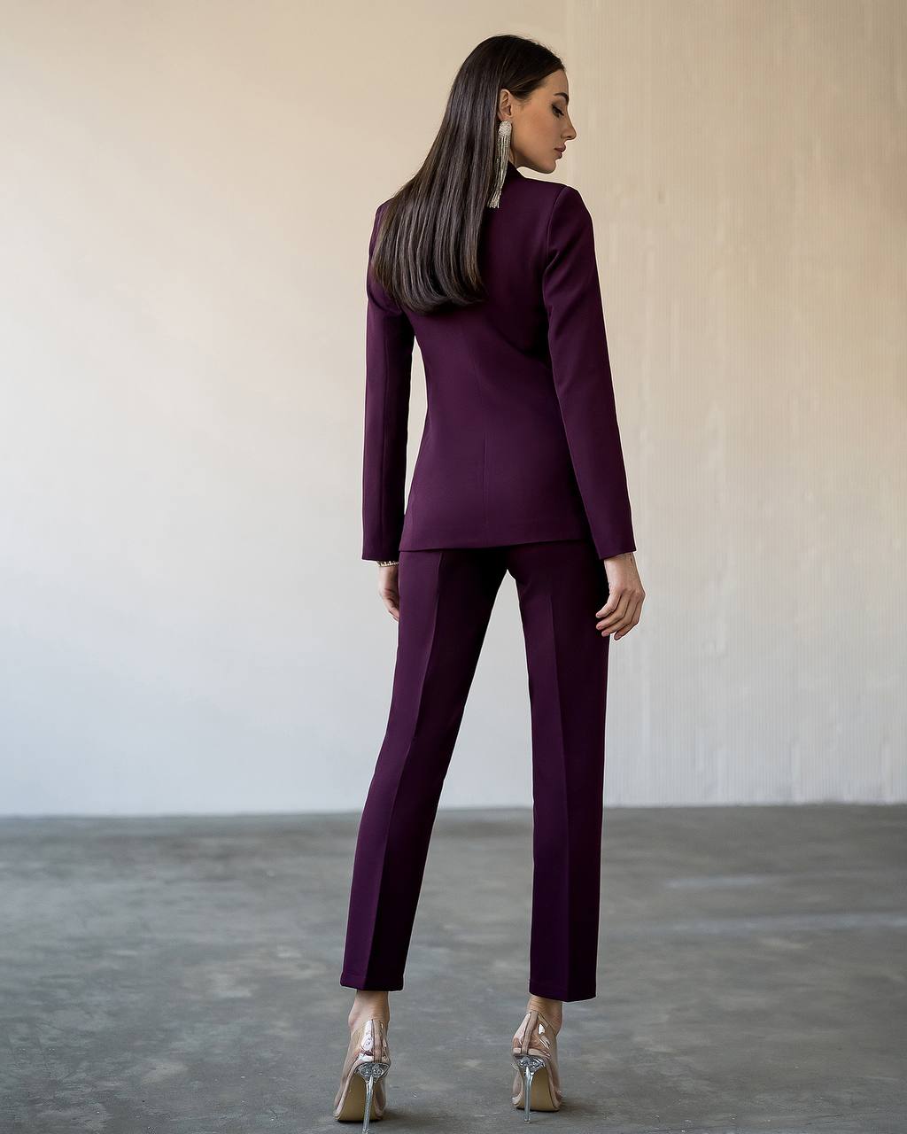 Woman wearing a purple suit standing against a plain background